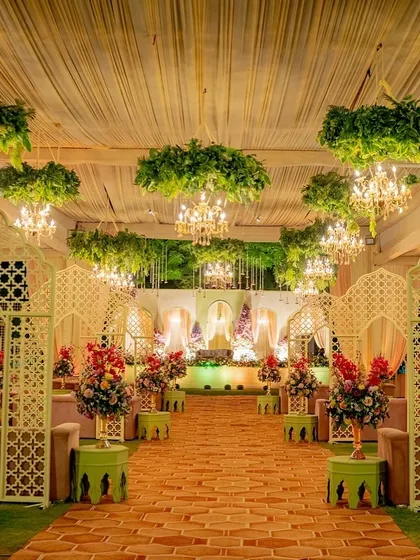 Imagine walking through an enchanted garden. I designed this elegant reception walkway with jaali arches, lush greenery suspended from the ceiling, and dozens of sparkling chandeliers. This design creates a truly magical pathway for you and your guests.