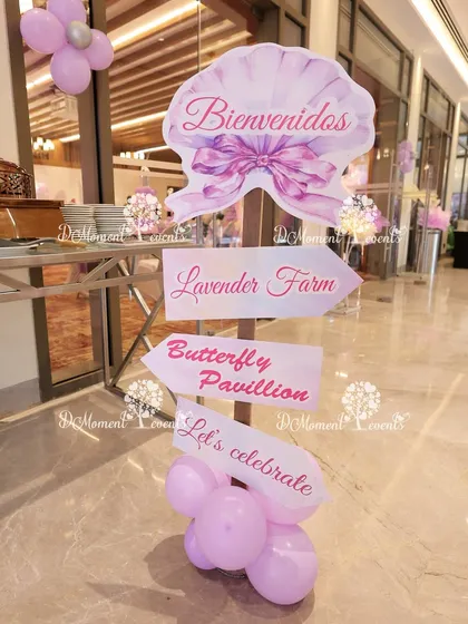 A charming directional signpost for a butterfly and lavender-themed party. The signs point guests to the "Lavender Farm" and "Butterfly Pavilion," adding a fun and interactive element to the decor.