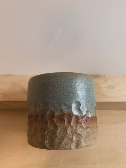 This mug features a beautiful contrast of textures, with a smooth, speckled blue glaze on top and a rough, carved texture on the unglazed bottom half. It's a piece you'll love to hold.