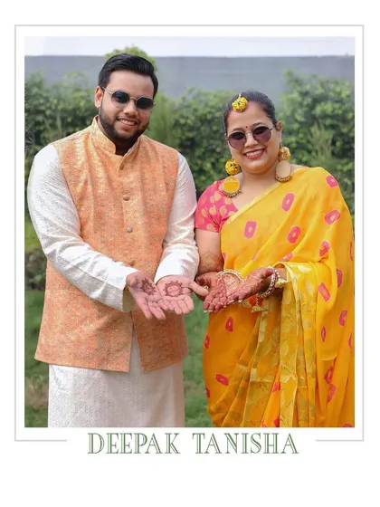 A portrait of the couple from their Haldi ceremony, showing their hands with turmeric paste.