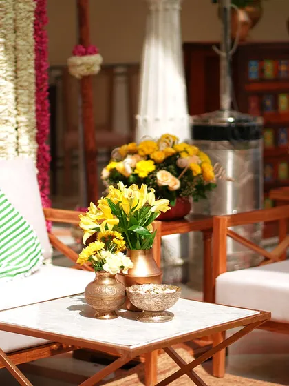A seating area with bright yellow flowers in brass vases, perfectly complementing the Haldi theme. Comfort and style go hand-in-hand in my event designs.