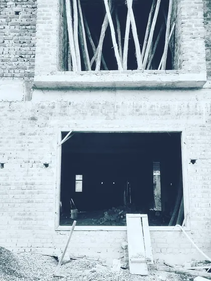 A black and white shot from a site visit, focusing on the raw structural openings of a building under construction. This is where the vision starts to take shape, with every window and door frame placed according to the architectural plan.
