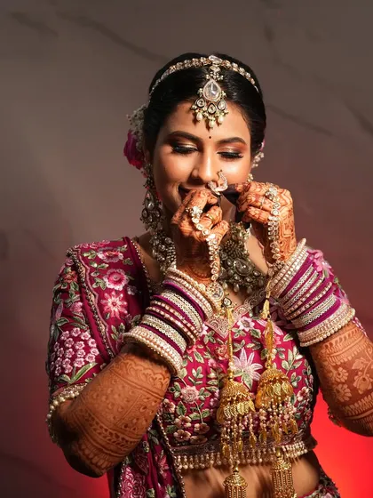 A playful moment with the bride adjusting her nose ring. This candid shot shows her joy and the intricate details of her look.