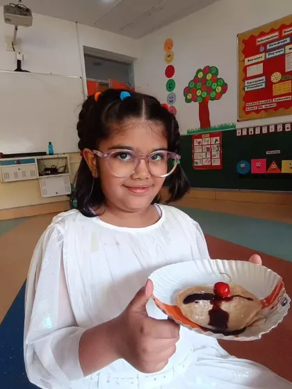 Our culinary arts program is a camp favorite, where children learn basic cooking skills and kitchen safety. This young chef proudly presents her chocolate-drizzled pancake, a delicious result of a hands-on session that combines creativity with practical life skills.