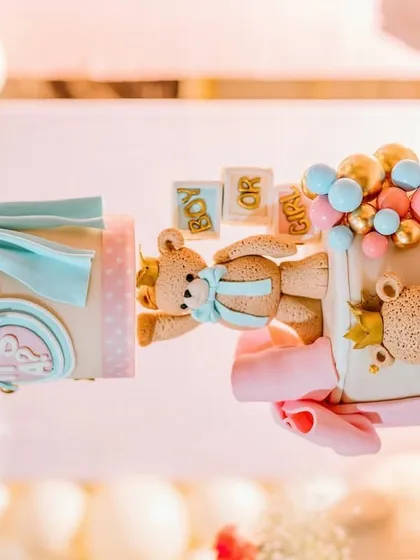 Even the cake can be part of the theme. This incredibly detailed cake features adorable teddy bears, bows, and a "Boy or Girl?" sign, perfectly matching the decor of the teddy bear gender reveal party.