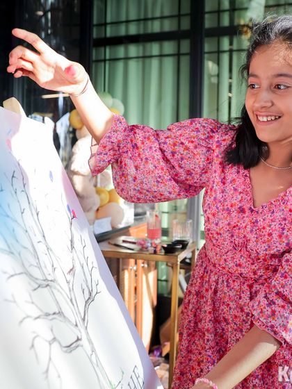 A young guest happily participates in the thumbprint gender reveal activity, adding her mark to the family tree.