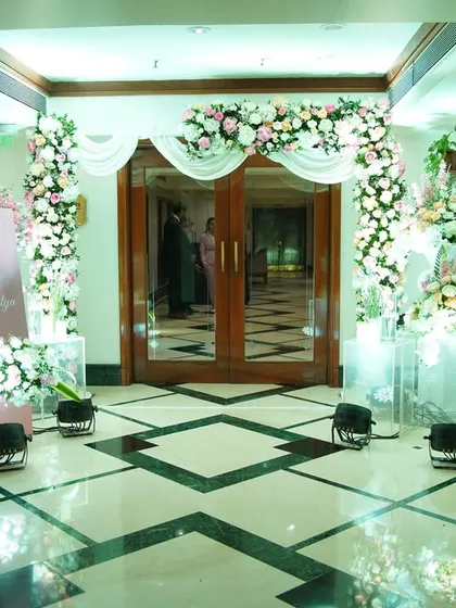 A soft and romantic entrance featuring a draped arch of white and pink florals, accented with candles for a warm and inviting glow.