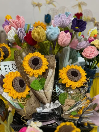 A vibrant display of our various crochet flower types, including sunflowers and tulips, ready for an exhibition. We love creating a rainbow of blooms.