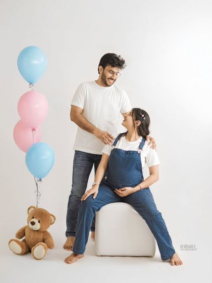 A fun and lighthearted maternity portrait with pink and blue balloons, hinting at a gender reveal. The couple's casual outfits and joyful expressions make this a sweet memory of their pregnancy journey.