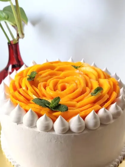 This mango rose cake is finished with a border of piped meringue kisses and fresh mint leaves, adding another layer of texture and freshness to the design.