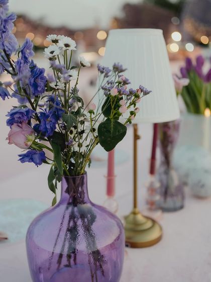 Exquisite table decorations featuring colored glass vases and simple but exotic flowers, adding a touch of sophistication and grace.