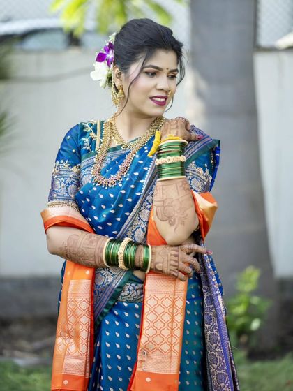 A stunning portrait of the bride in her royal blue Paithani saree, looking elegant and poised.