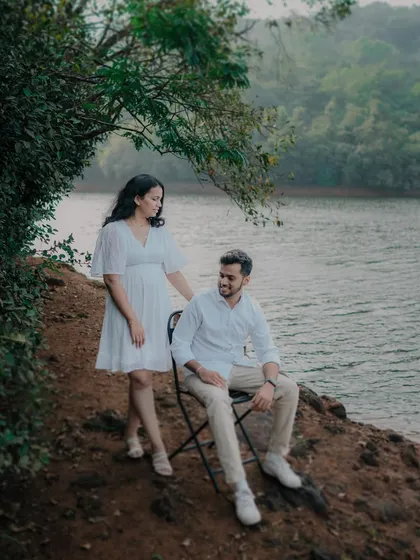 A serene lakeside portrait near Pune. The composition, with the bride standing by the seated groom, feels calm and contemplative, perfectly matching the tranquil environment.