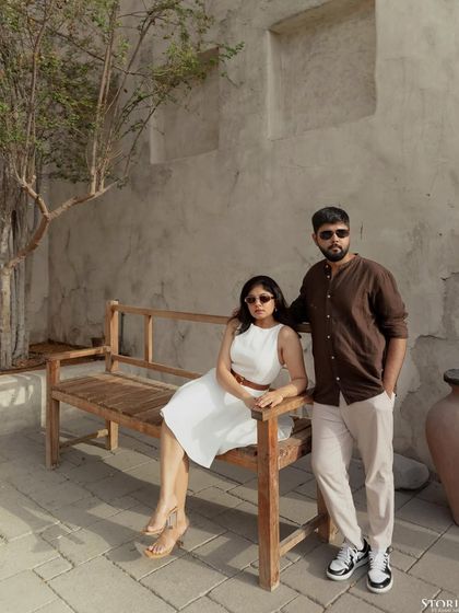 A relaxed portrait of the couple on a wooden bench, a moment of calm and connection.