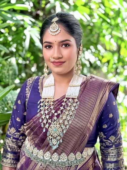 A direct portrait highlighting the magnificent statement necklace and the client's glowing skin.