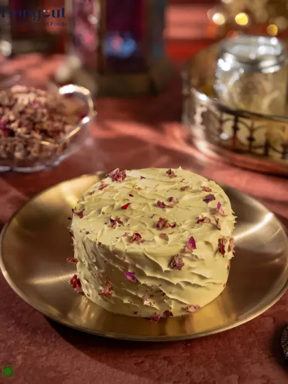 A perfect example of our fusion desserts, this is the Pistachio Rasmalai Bento Cake. It combines the traditional Indian flavor of rasmalai with nutty pistachio, all wrapped in a modern bento cake format and decorated with delicate rose petals.