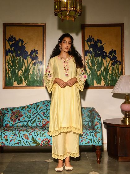 A full-length portrait for Baavli's festive collection. The vibrant yellow outfit stands out beautifully against the art-filled interior.