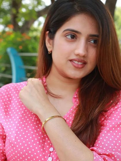 A woman in a pink shirt casually wears a thin gold cuff bracelet, showing its suitability for everyday, comfortable style.