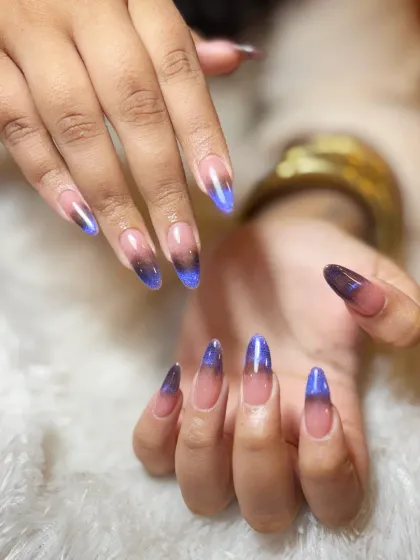 A full view of the stunning blue and black cat-eye ombre on long, almond-shaped extensions.