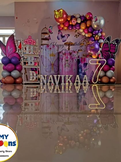 A butterfly-themed seventh birthday with a reflective floor. The purple and silver decor, neon '7', and butterfly cutouts create a modern and stylish look.