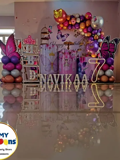 A butterfly-themed seventh birthday with a reflective floor. The purple and silver decor, neon '7', and butterfly cutouts create a modern and stylish look.