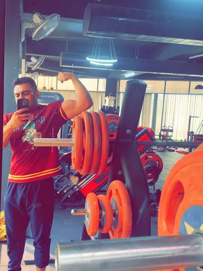 A quick flex after a good session. This client is showing the results of his arm workout. Building muscle mass requires consistent effort and heavy lifting, and he is putting in the work.