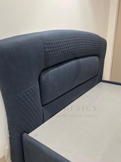 This bed in a deep navy blue features a curved headboard with quilted side panels. It also includes a hydraulic lift mechanism, providing a smart and spacious storage solution.