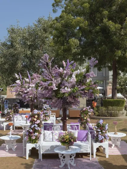 A wide shot of the lavender-themed event space, with blooming trees and coordinated lounge furniture creating a cohesive and dreamy landscape.