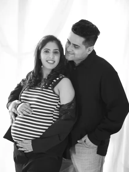 A lovely black and white couple's portrait in casual wear. The partner looks lovingly at the mother-to-be as she smiles at the camera.