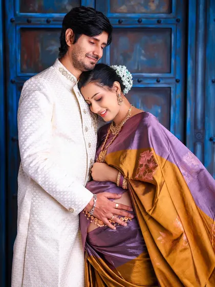 The bond between partners shines through in this elegant traditional maternity portrait. Dressed in a beautiful silk saree, the couple shares a quiet, loving moment, showcasing a timeless connection.
