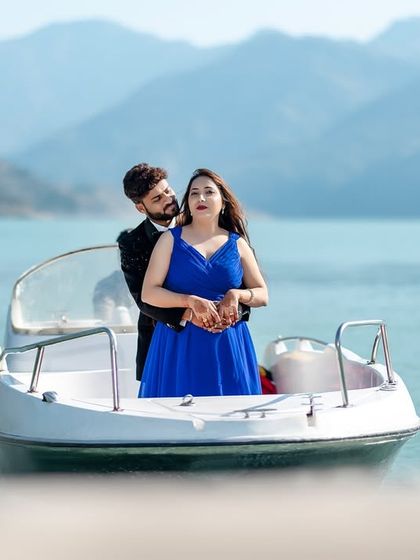 A classic portrait of the couple embracing on the boat. The calm water and distant mountains provide a simple yet beautiful setting for this engagement photo.