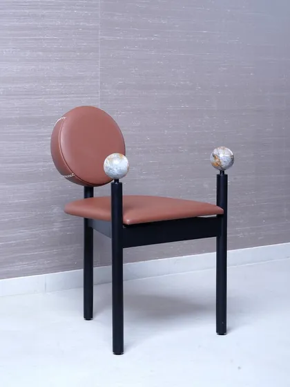 We designed this chair as a piece of art, combining a terracotta leather seat and backrest with a sleek black frame. The design is elevated by two polished marble spheres that serve as unique armrest finials, blending natural stone with modern furniture design.
