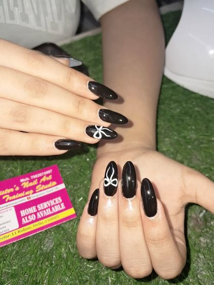 A chic and simple design with glossy black almond-shaped nails and a single, hand-painted white bow on each hand.