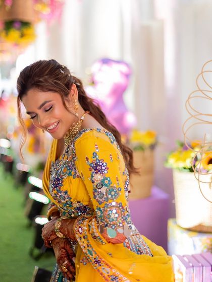 A happy, candid moment from the haldi ceremony. The makeup is light and fresh, allowing the bride's joyful expression to be the focus.