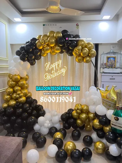 A classic half-arch balloon decoration for a birthday party. The black, gold, and white color scheme is timeless, and the setup includes fun elements like a champagne bottle balloon.
