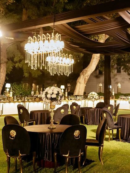 A luxurious lounge area with modern chandeliers, plush black seating, and chairs with gold lion-head details, creating a sophisticated and comfortable space for guests.