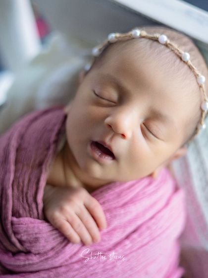 A close-up on the tiny details, from the pearl headband to the little mouth, in the pink bougainvillea shoot.