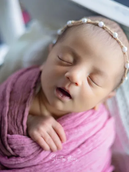 A close-up on the tiny details, from the pearl headband to the little mouth, in the pink bougainvillea shoot.