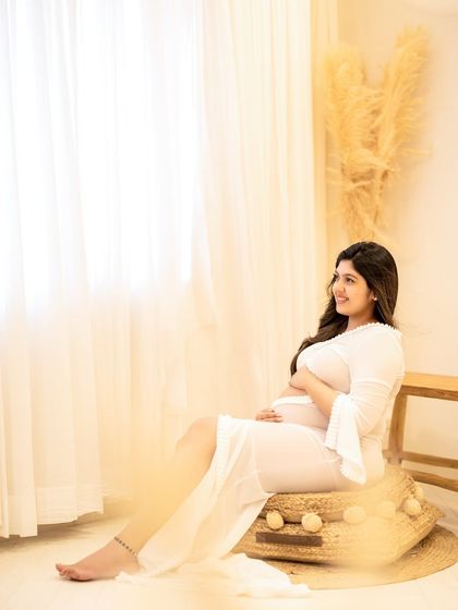A relaxed, seated pose on a jute pouf, creating a comfortable and bohemian vibe for this solo maternity portrait.