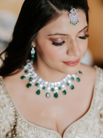 A close-up of the bride's flawless makeup and stunning diamond and emerald necklace, highlighting her radiant beauty.