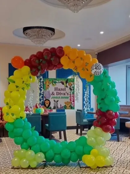 A circular jungle-themed balloon arch perfect for a photo booth at a banquet hall. The arch is decorated with colorful balloons and a lion foil balloon topper.