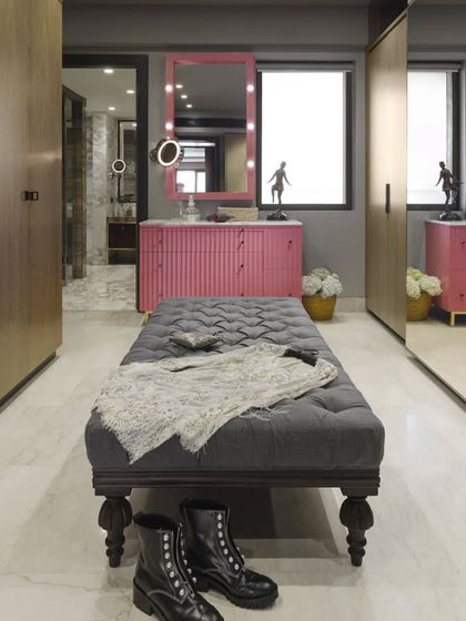 The master dressing room in the Caitriona apartment is pure glamour and function. Mirrored wardrobes on one side expand the space, while a high-gloss pink dressing table with Hollywood-style lights adds a touch of playful luxury.