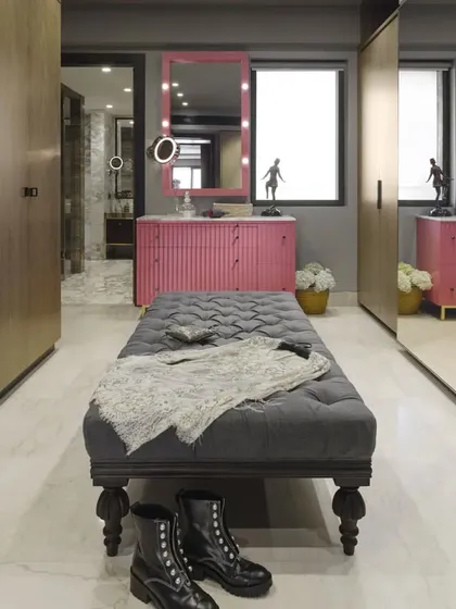 The master dressing room in the Caitriona apartment, featuring an ash-pink dressing table and a large, velvety upholstered ottoman. The space is both glamorous and functional, with mirrored sliding shutters on the wardrobes.
