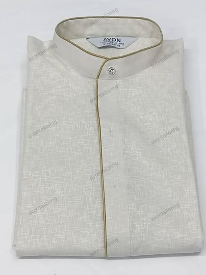 This off-white textured kurta is paired with a subtle golden piping. It is sold as a complete set with a matching saya and izaar.