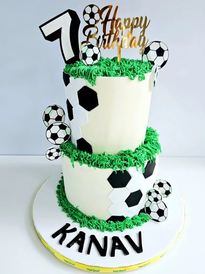 Another take on the popular football theme, this two-tier cake is covered in a soccer ball pattern. The green buttercream 'grass' and personalized name make it a winning choice for any fan.
