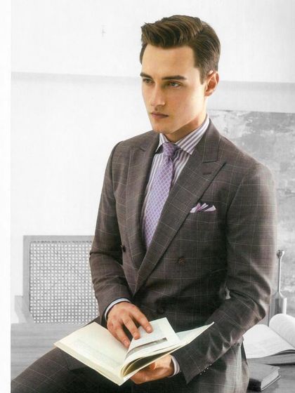 A classic double-breasted suit in grey plaid, paired with a lavender shirt. This demonstrates our ability to create sophisticated business attire that is both timeless and modern.