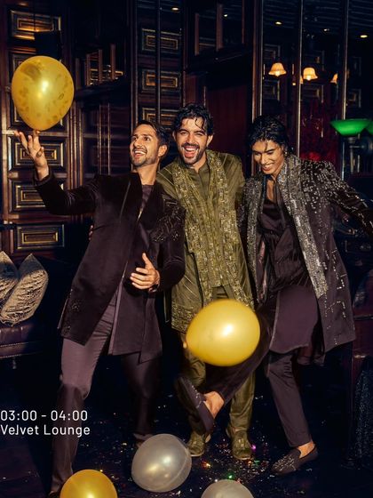 The celebration continues in the Velvet Lounge. This image captures the joy of the night, with men dressed in my olive and wine velvet ensembles. The confetti and balloons highlight that these are clothes made for making memories.