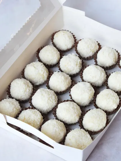 A box filled with my delicate coconut truffles. The soft, sweet coconut coating provides a beautiful contrast to the rich chocolate center, making it a favorite for festive platters.