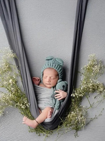 Gently cradled and surrounded by delicate baby's breath. This hanging prop pose is one of our favorites for creating an artistic and ethereal newborn photograph, highlighting how small and precious they are.