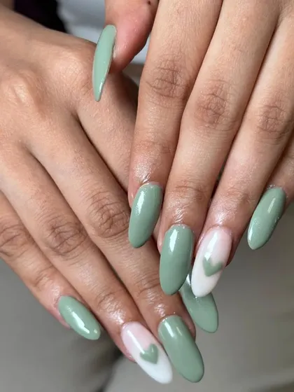 A soft and trendy look featuring a pastel sage green polish with negative space heart accent nails.